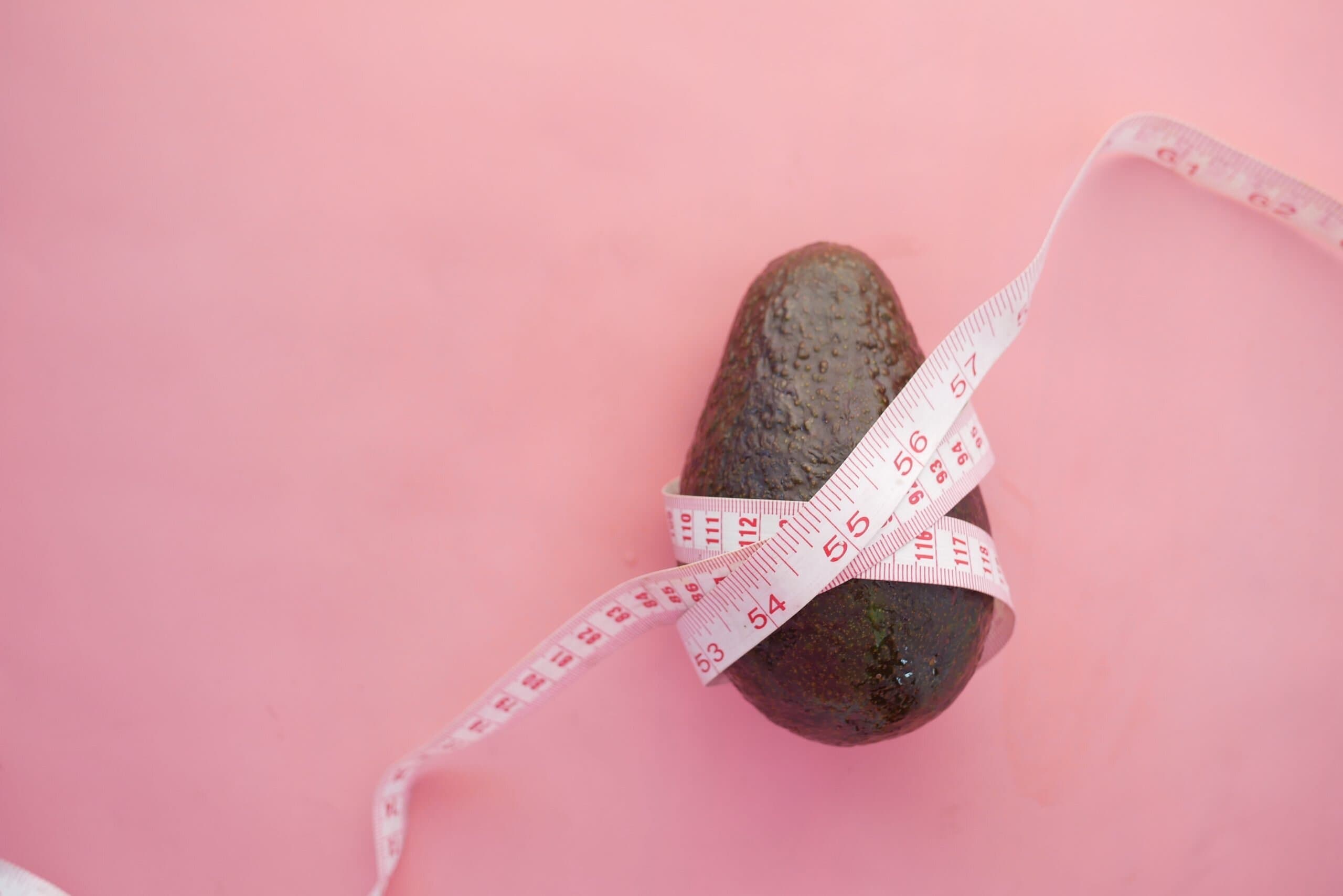 pink background with an advocado with measuring tape