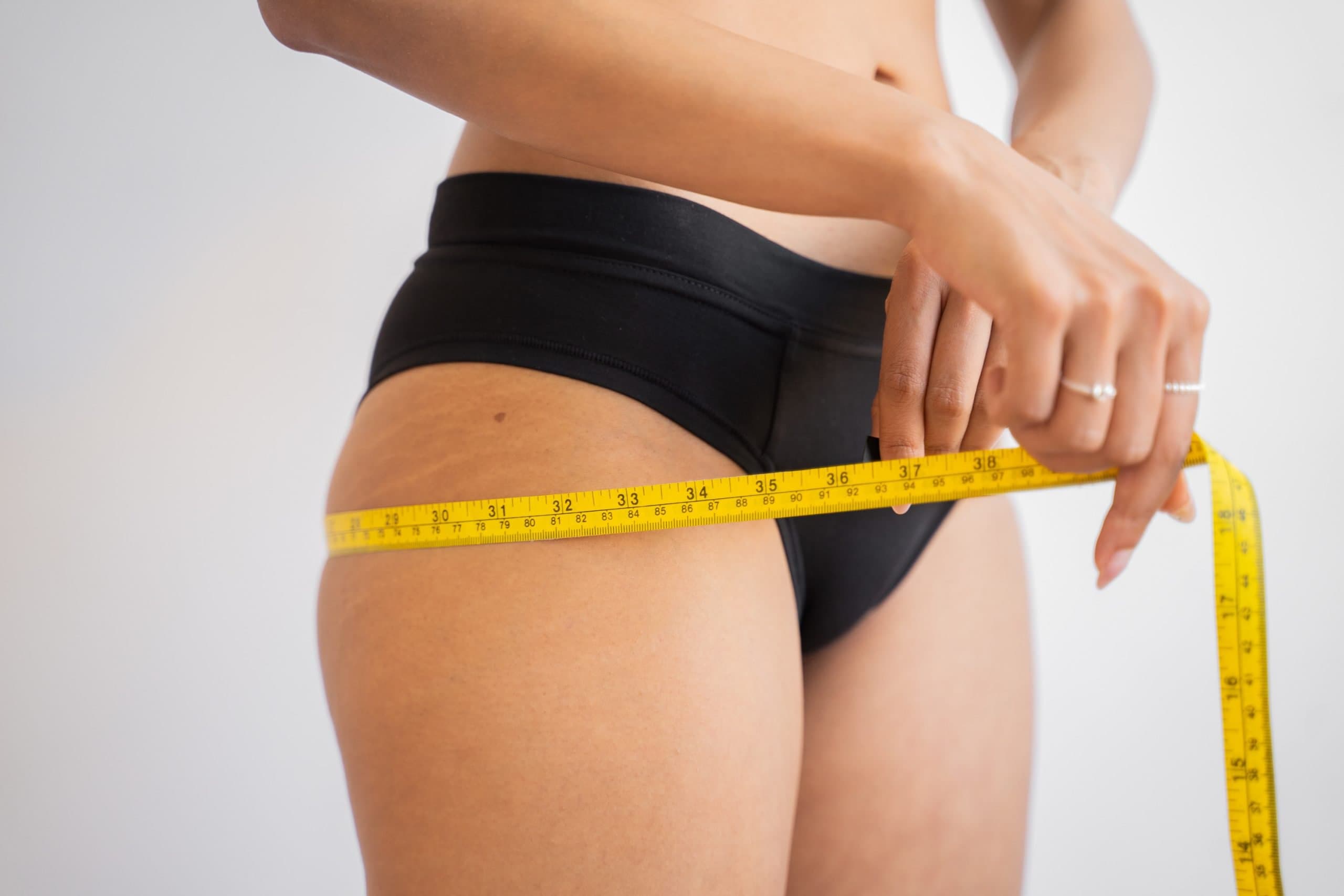 A person measuring her hips with a measuring tape
