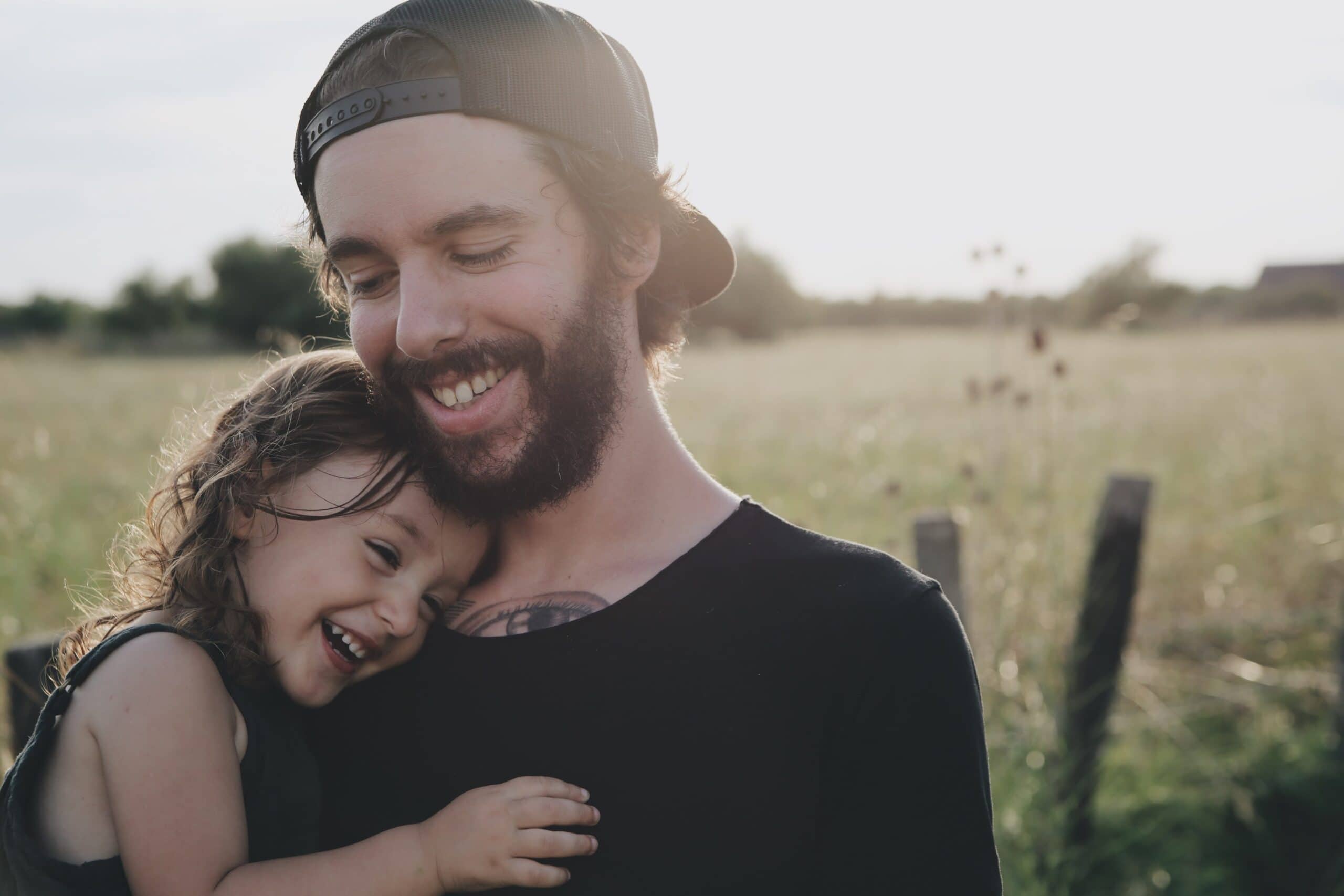 A man in a black tshirt cuddling his daughter