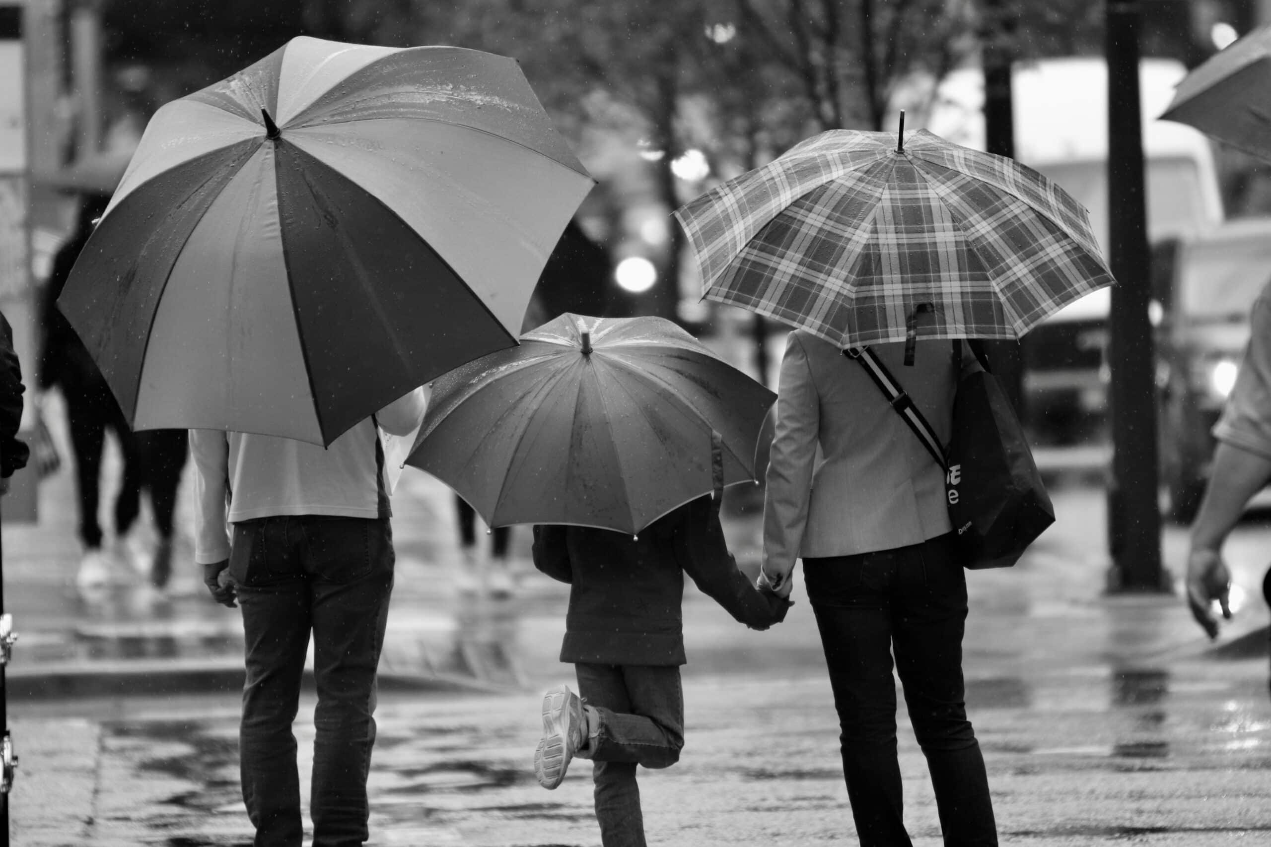 Two adults and a child with umbrellas